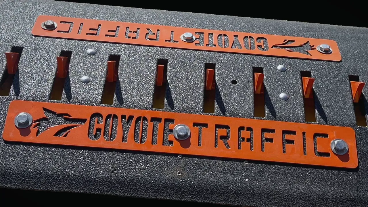 Close-up of orange laser-cut Coyote Traffic faceplates bolted on a surface-mounted spike module
