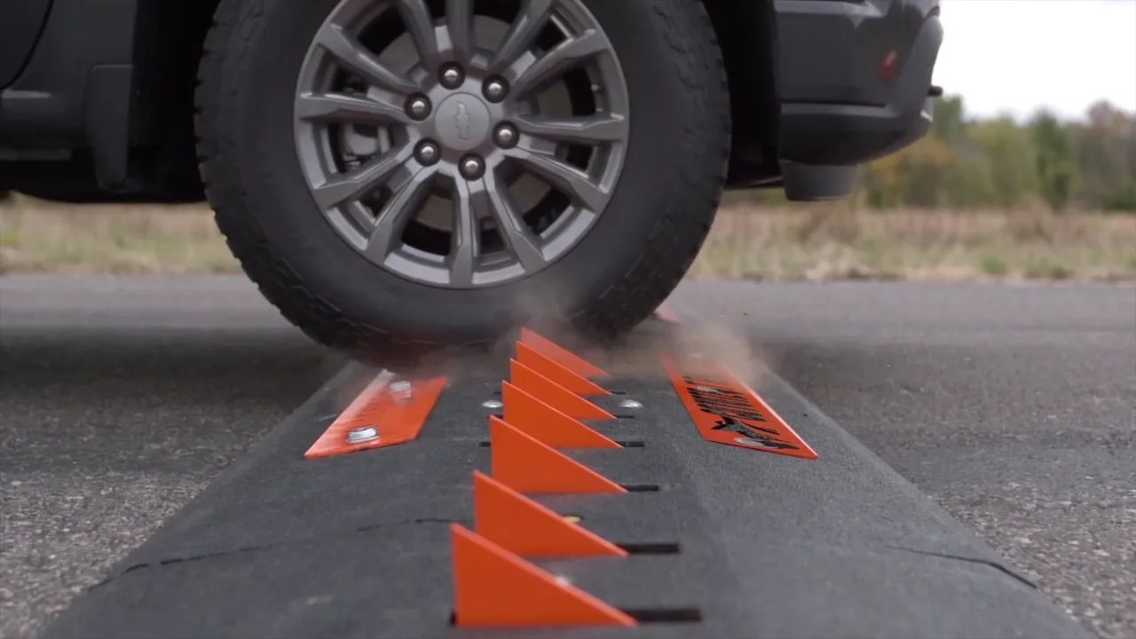 Pickup tire rolling onto the orange teeth of a Coyote Traffic surface-mounted spike strip during a wrong-way test