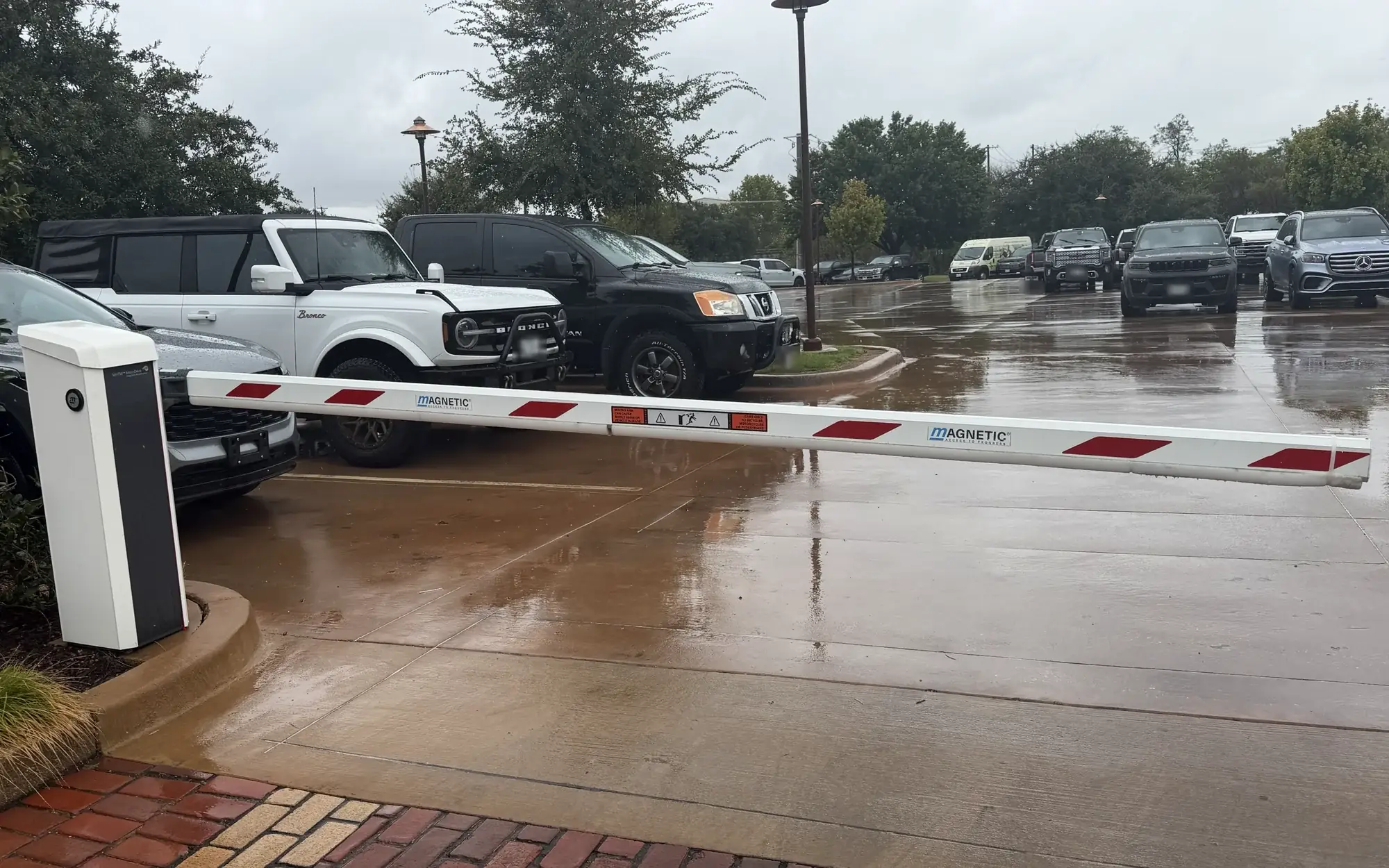 Magnetic barrier gate with a red-and-white striped arm closing a lane at a Texas parking lot