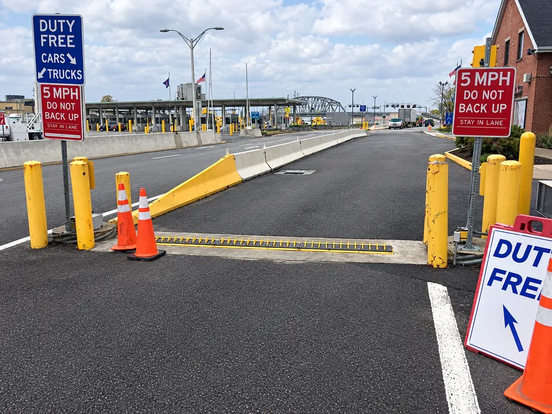 In-ground spikes across a lane at a border-crossing duty-free exit with bollards and cones