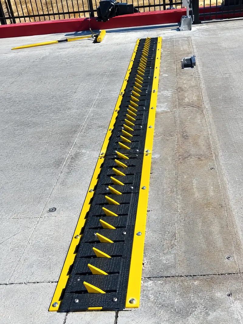 Close-up of in-ground spikes with yellow blades in a flush black cover plate set in concrete
