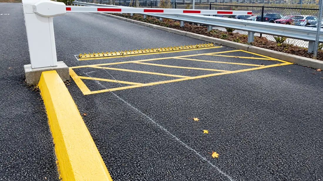 In-ground spikes across an exit lane at a gate arm with yellow hatch markings