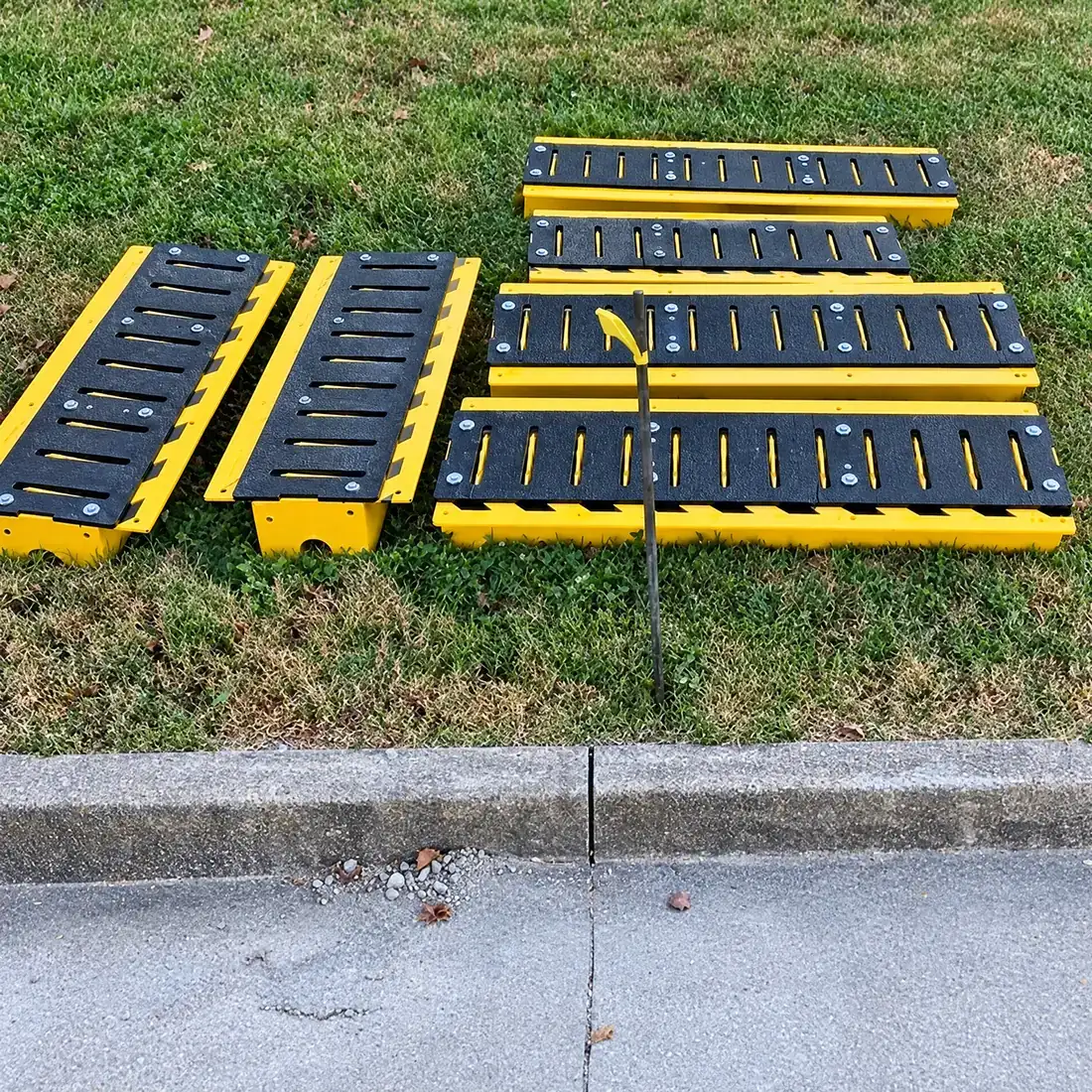 Several in-ground spike sections laid out on grass before installation