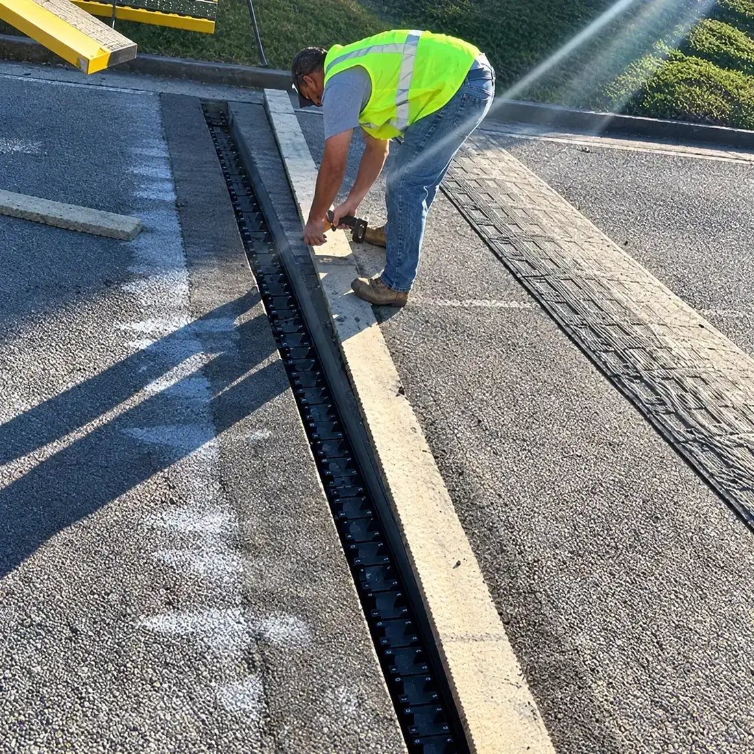 Installer setting an in-ground spike frame into a saw-cut trench