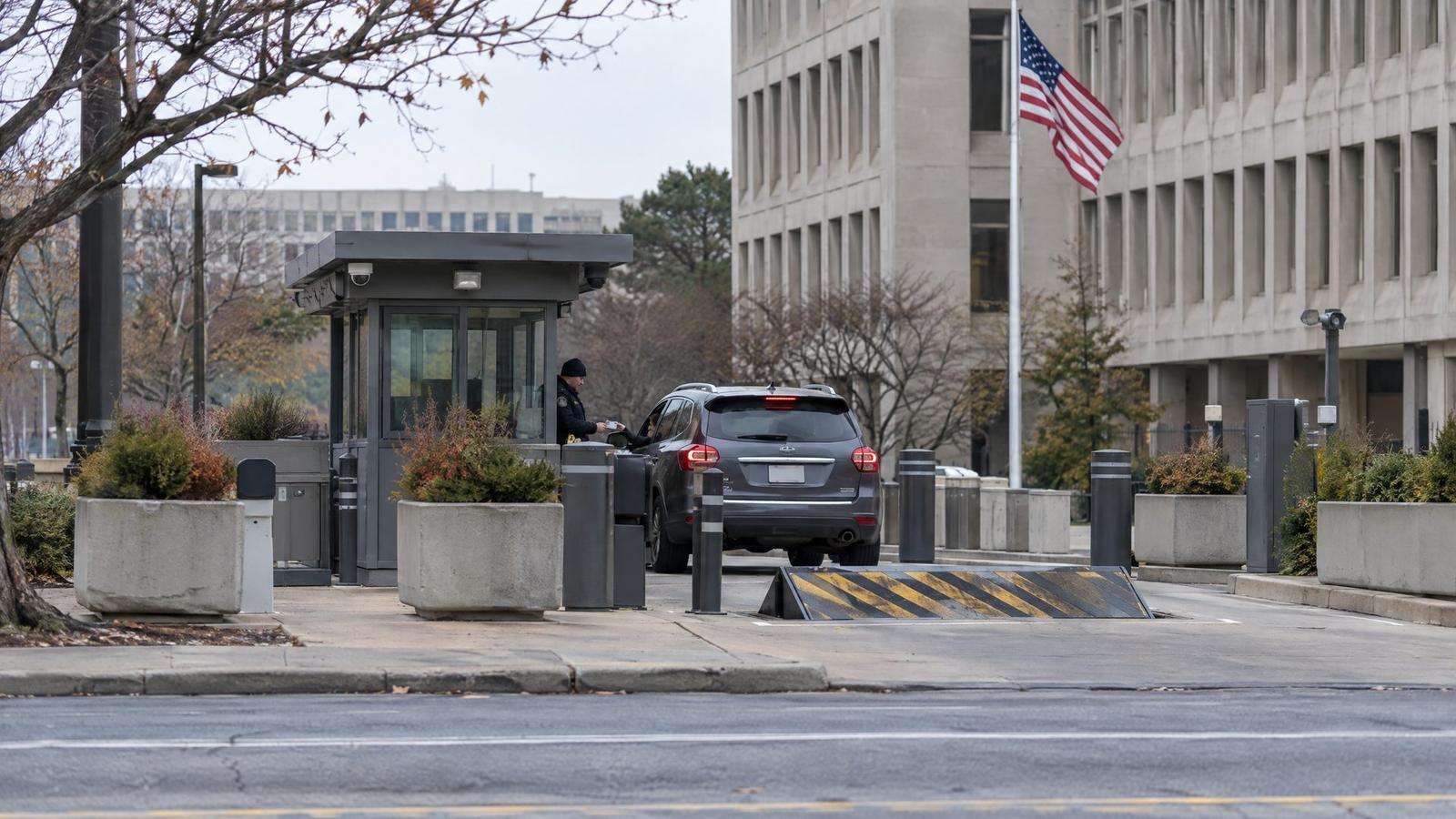 Guarded vehicle checkpoint with a wedge barrier and bollards outside a federal office building