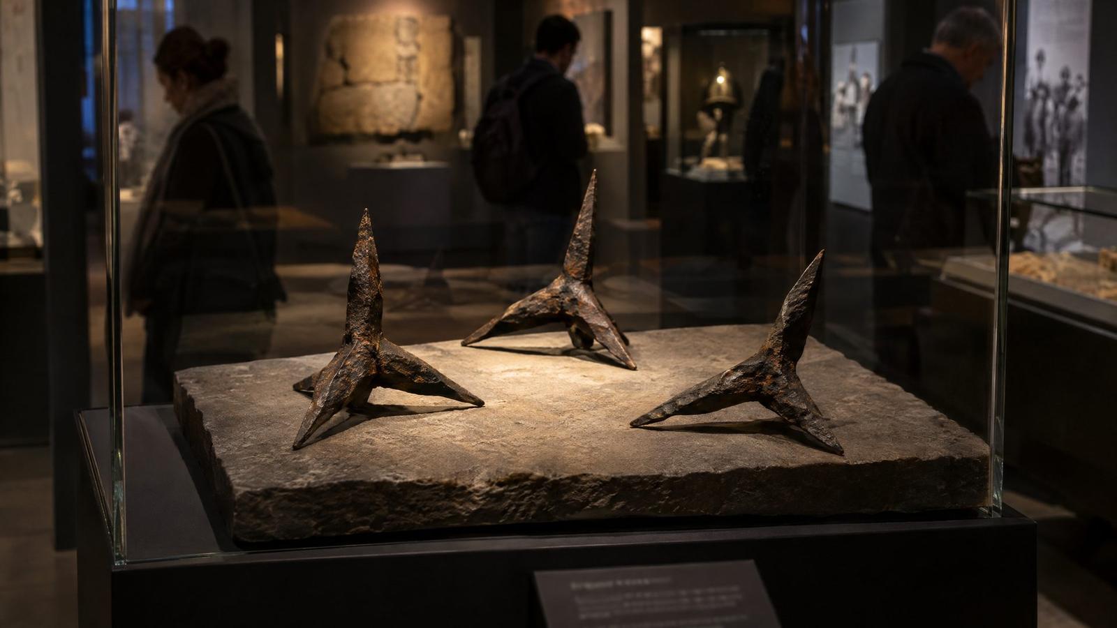 Antique iron caltrops displayed on a stone plinth in a museum case