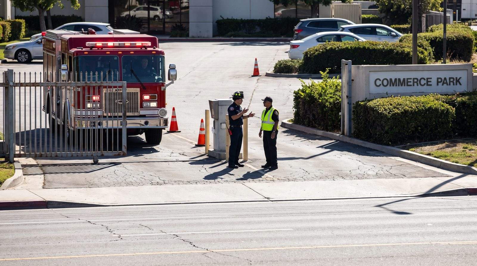 Fire captain and gate contractor discussing emergency access at a commercial park entrance with a fire engine waiting