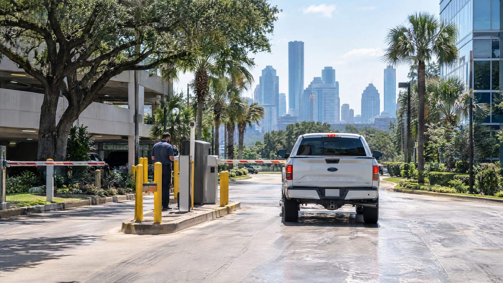 Pickup truck waiting at a parking garage exit gate with the Houston skyline in the distance