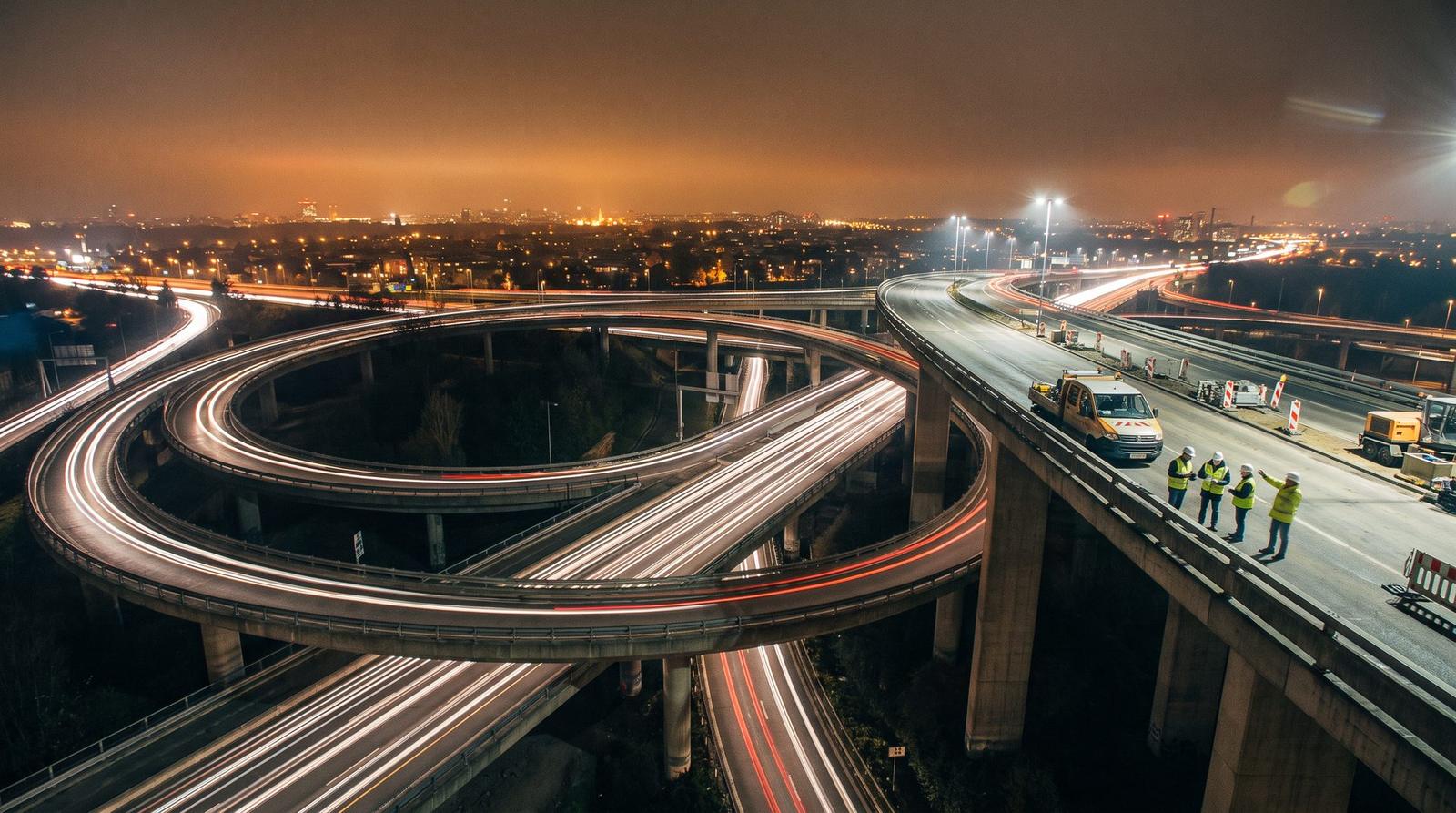 Night long exposure of a multi-level highway interchange with a work crew on the overpass
