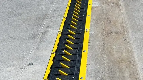 In-ground traffic spike section with yellow teeth set flush in concrete