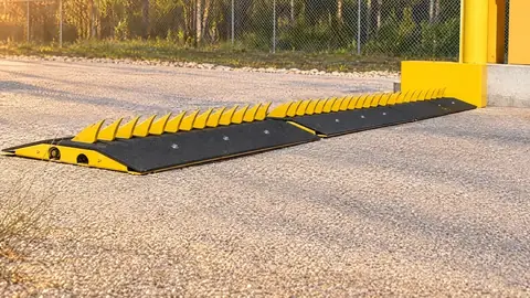 Motorized traffic spike system with yellow teeth raised beside a gate