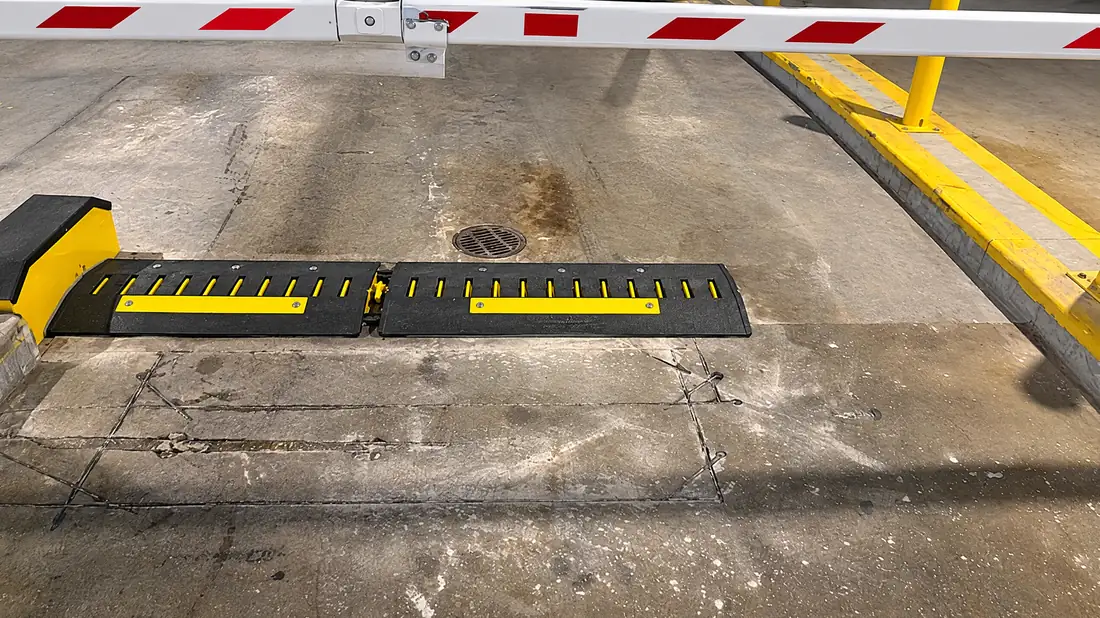 Two motorized spike modules in a parking-garage exit lane under a striped gate arm
