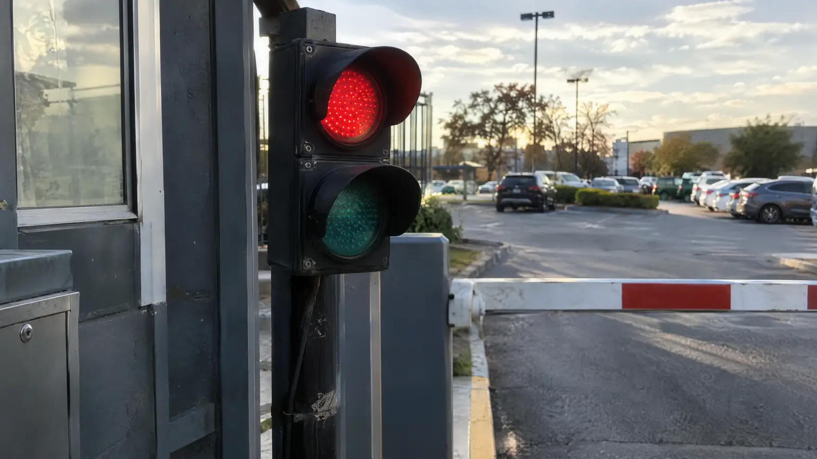 Red and green LED entry signal light on a post next to a parking barrier gate arm