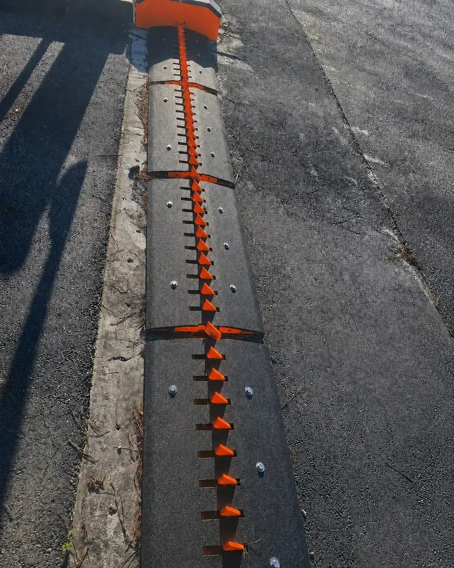 Overhead view of an orange-tooth spike strip installed in a median lane