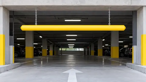 Yellow clearance bar hanging on chains at a parking garage entrance