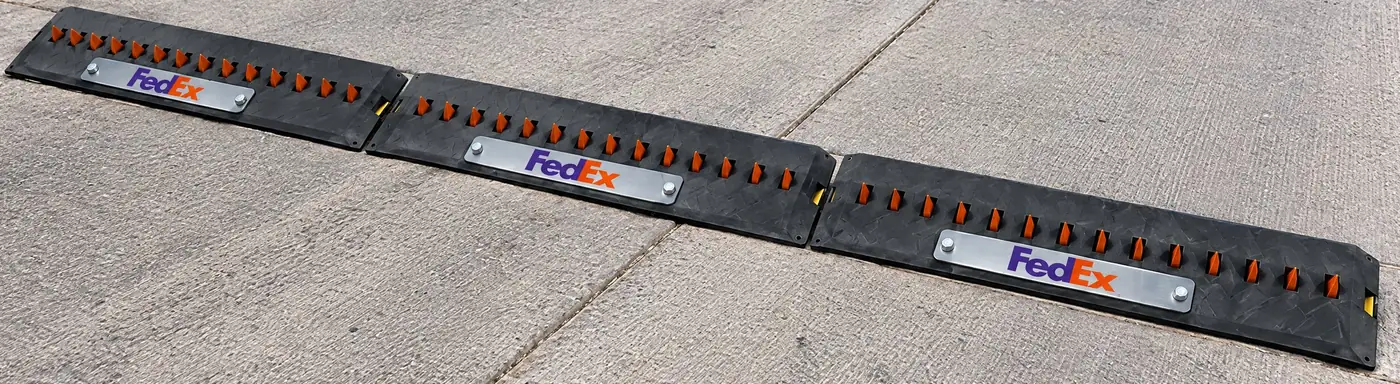 Three spike modules with brushed-steel FedEx faceplates bolted across a concrete yard lane